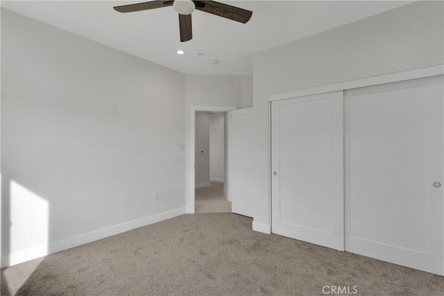 unfurnished bedroom featuring ceiling fan, a closet, and light carpet