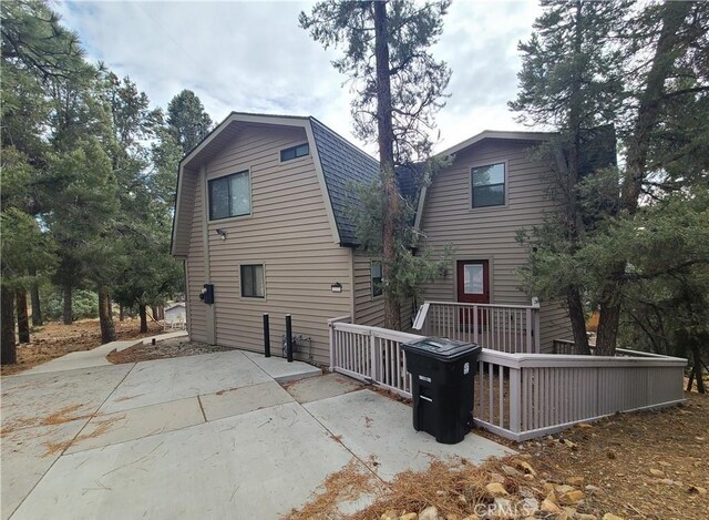 back of house featuring a wooden deck and a patio