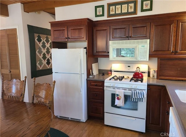 kitchen with white appliances, light hardwood / wood-style flooring, and beamed ceiling