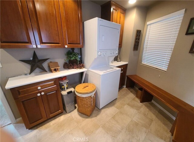 washroom featuring cabinets and stacked washer and clothes dryer