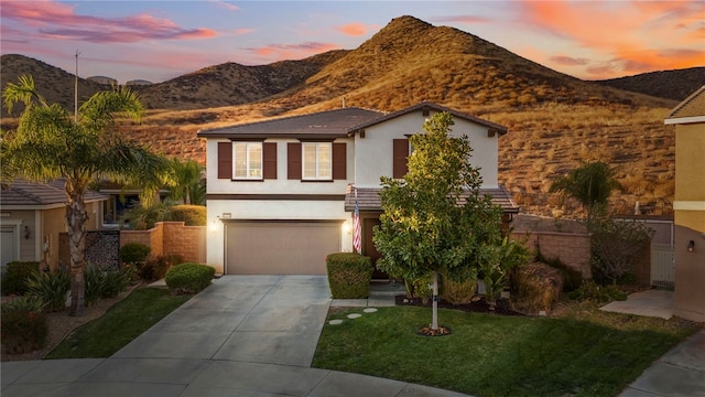 view of front of property featuring a garage, a mountain view, and a lawn