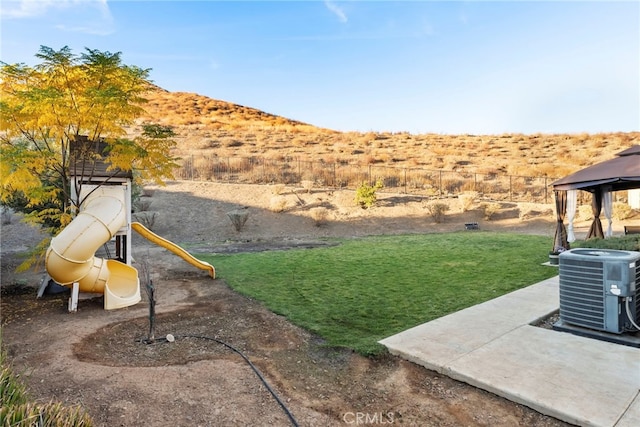 view of yard featuring a playground, central air condition unit, and a mountain view