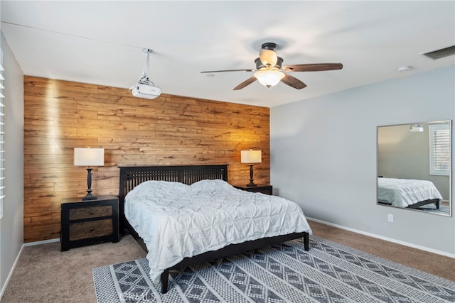 carpeted bedroom with ceiling fan and wooden walls