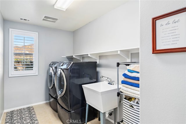 washroom with sink, washing machine and clothes dryer, and light tile patterned floors