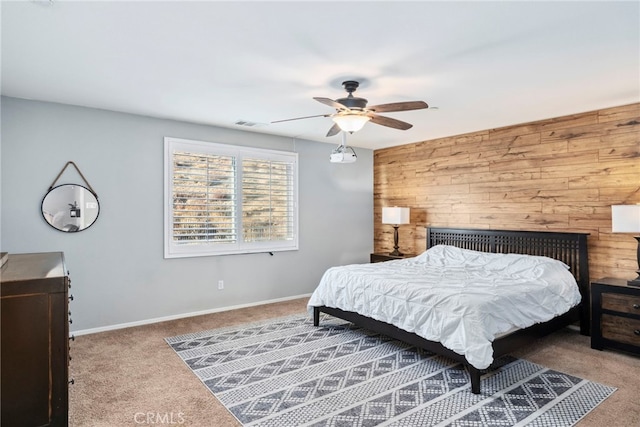 bedroom featuring wooden walls, carpet floors, and ceiling fan