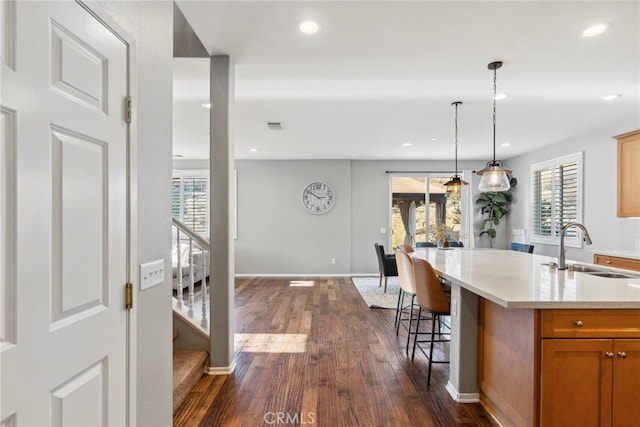 kitchen with an island with sink, hanging light fixtures, a wealth of natural light, and sink