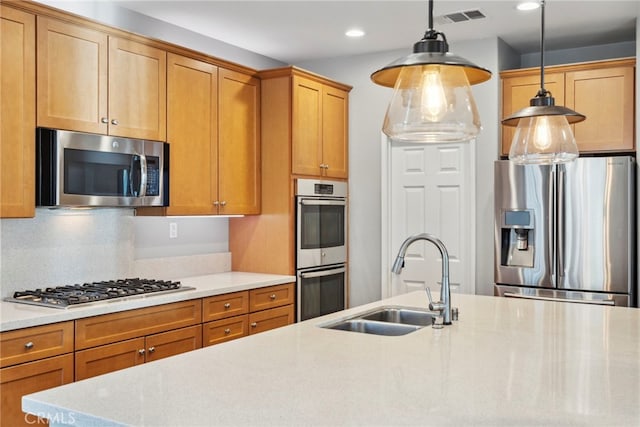 kitchen featuring appliances with stainless steel finishes, light stone countertops, sink, decorative light fixtures, and tasteful backsplash