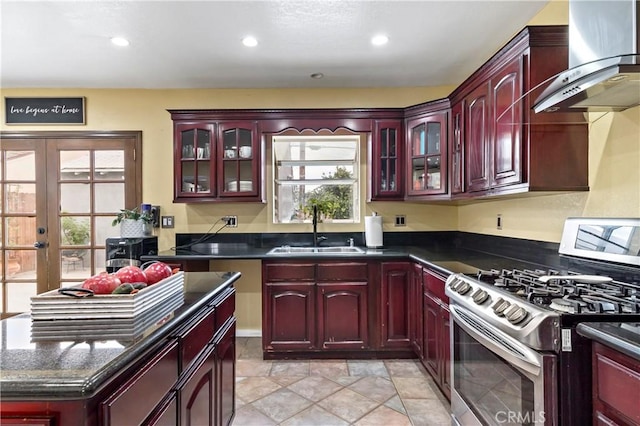 kitchen featuring stainless steel range with gas cooktop, sink, wall chimney exhaust hood, and french doors