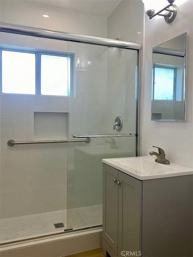 bathroom with vanity, a shower with door, and a wealth of natural light