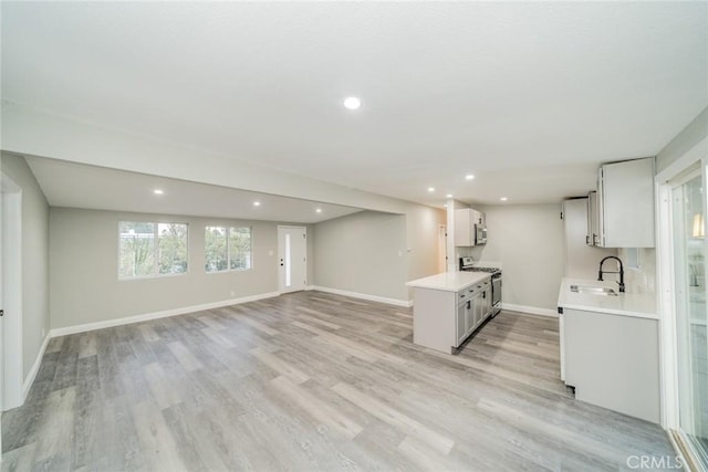 interior space with sink, white cabinets, stainless steel appliances, and light hardwood / wood-style floors