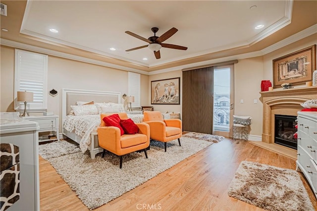 bedroom featuring a raised ceiling, light hardwood / wood-style flooring, ceiling fan, and ornamental molding