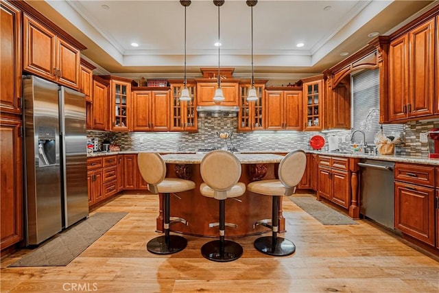 kitchen featuring a center island, backsplash, light hardwood / wood-style flooring, light stone countertops, and appliances with stainless steel finishes