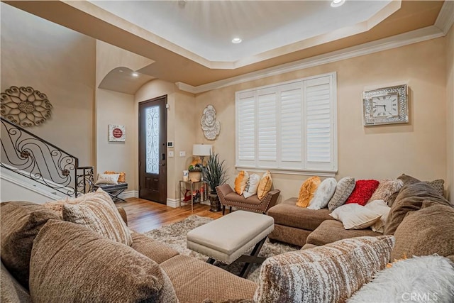 living room featuring light wood-type flooring, a tray ceiling, and crown molding