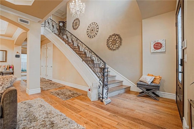 staircase featuring hardwood / wood-style flooring, an inviting chandelier, and crown molding