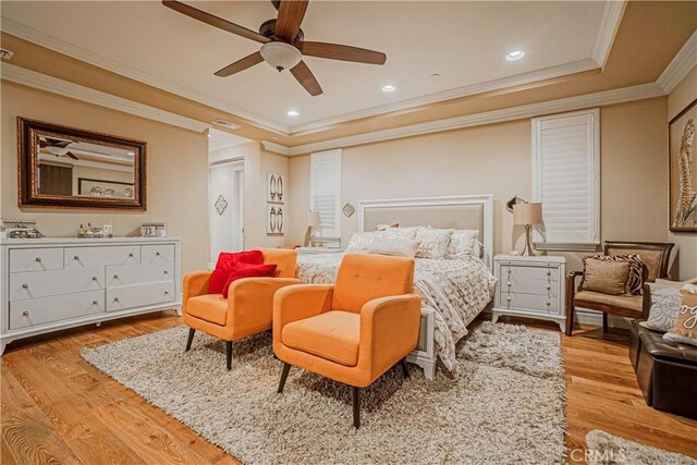 bedroom featuring a tray ceiling, ceiling fan, light hardwood / wood-style floors, and ornamental molding