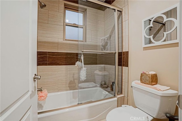 bathroom featuring toilet and bath / shower combo with glass door