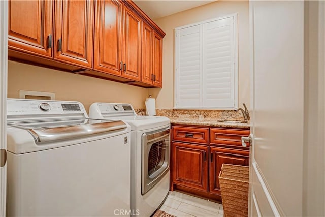 laundry area with sink, light tile patterned floors, cabinets, and independent washer and dryer