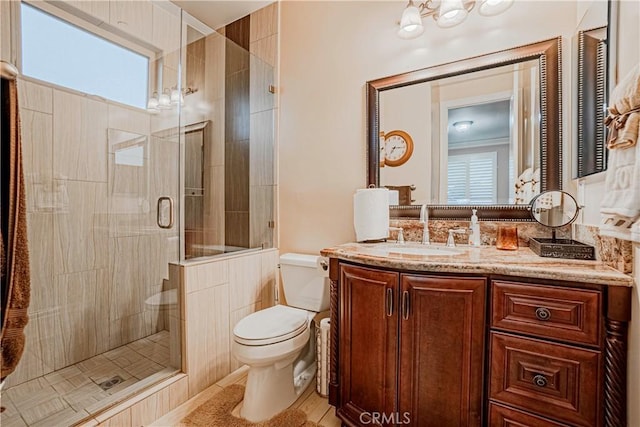 bathroom featuring tile patterned flooring, vanity, a shower with shower door, and toilet