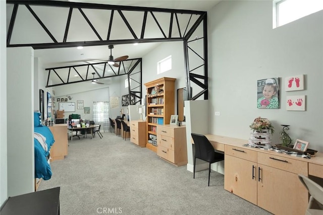 carpeted office space featuring a high ceiling and ceiling fan