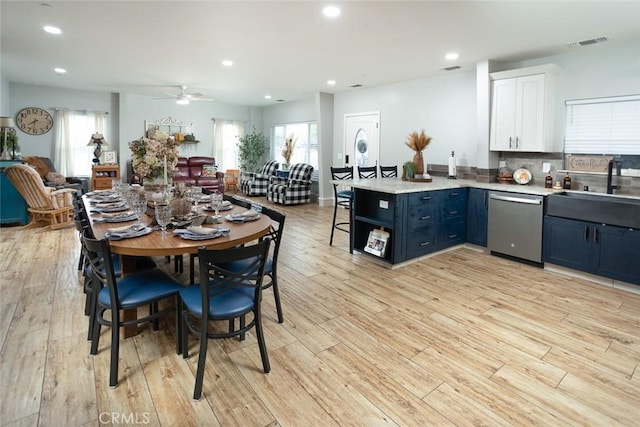 dining space with ceiling fan, sink, and light wood-type flooring