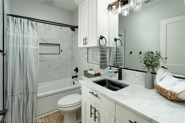 full bathroom featuring tiled shower / bath combo, toilet, wood-type flooring, and vanity