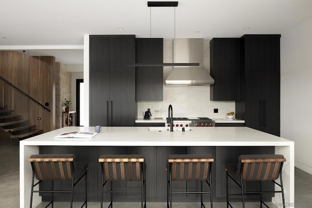 kitchen featuring a kitchen bar, decorative light fixtures, a spacious island, and wall chimney range hood