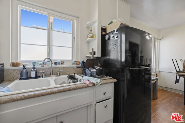 kitchen with black fridge, white cabinetry, sink, and dark hardwood / wood-style floors