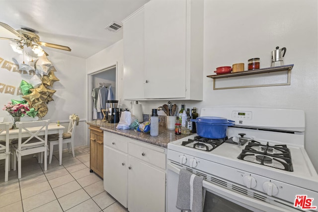 kitchen featuring white cabinets, light tile patterned floors, white gas range, and ceiling fan