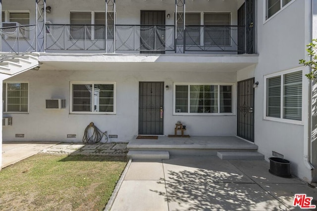 doorway to property featuring a patio area, a balcony, a yard, and a wall mounted AC