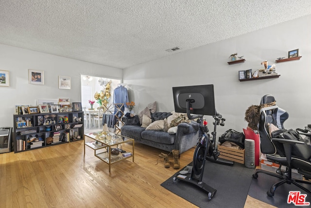 exercise area with hardwood / wood-style floors and a textured ceiling