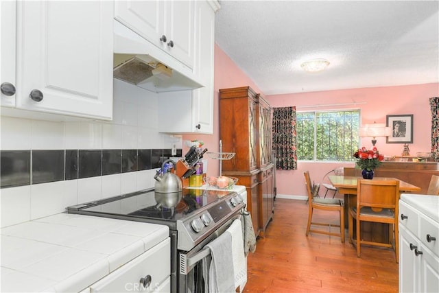 kitchen featuring white cabinets, appliances with stainless steel finishes, tile countertops, and light hardwood / wood-style floors