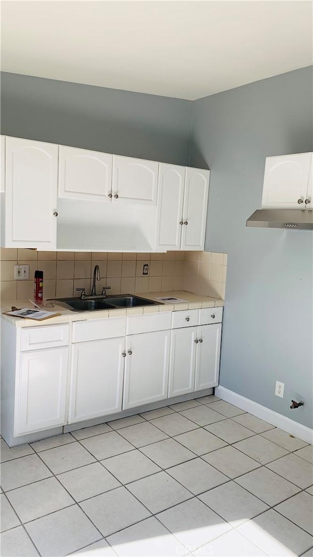 kitchen with tasteful backsplash, white cabinetry, and sink