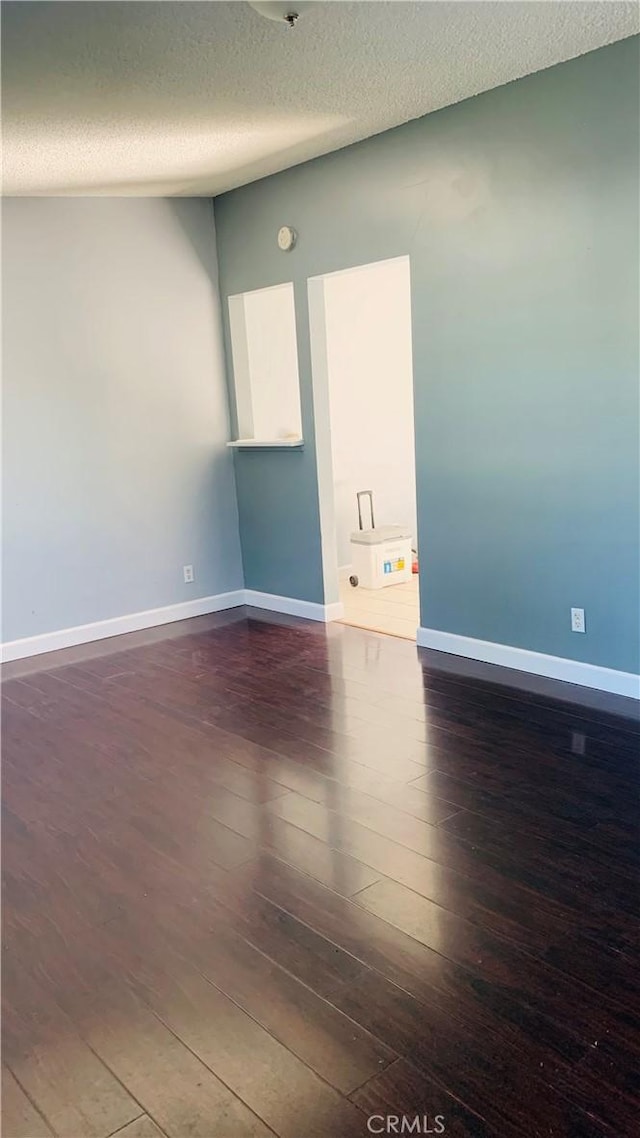 unfurnished room featuring a textured ceiling and dark hardwood / wood-style floors