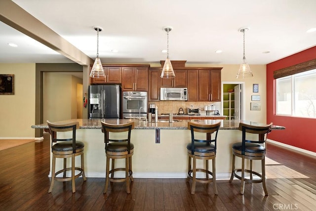 kitchen featuring a kitchen breakfast bar, dark wood-type flooring, an island with sink, and stainless steel appliances