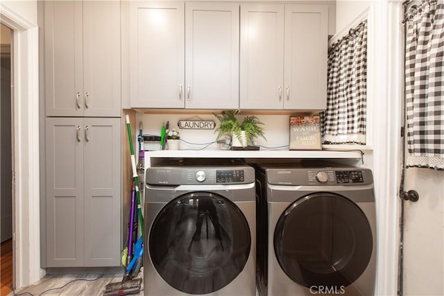 clothes washing area featuring washer and clothes dryer, cabinets, and light wood-type flooring