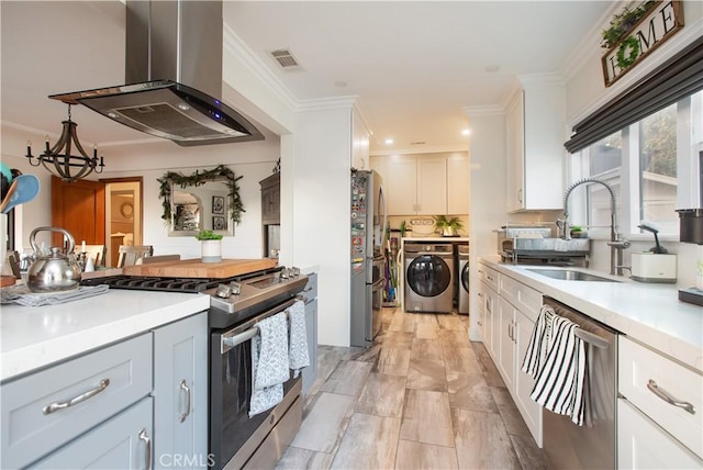 kitchen with sink, independent washer and dryer, white cabinetry, island exhaust hood, and stainless steel appliances