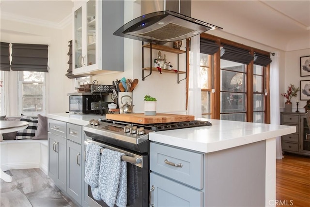 kitchen featuring white cabinetry, stainless steel range, light hardwood / wood-style flooring, island exhaust hood, and crown molding