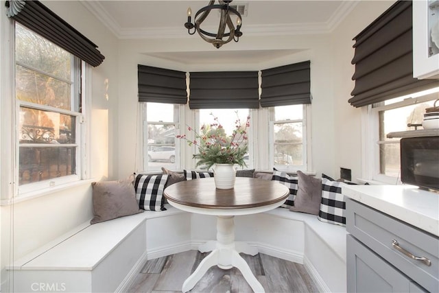 dining area featuring a healthy amount of sunlight, breakfast area, light hardwood / wood-style flooring, and ornamental molding