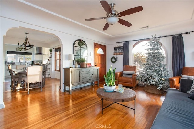 living room featuring ceiling fan with notable chandelier and hardwood / wood-style flooring