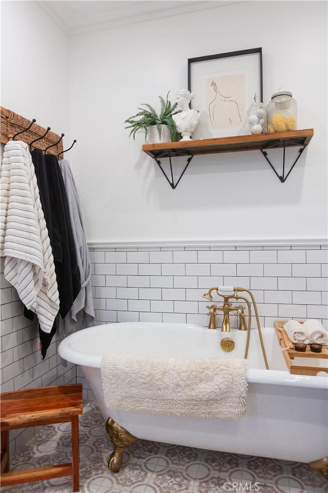 bathroom with a washtub, crown molding, and tile walls