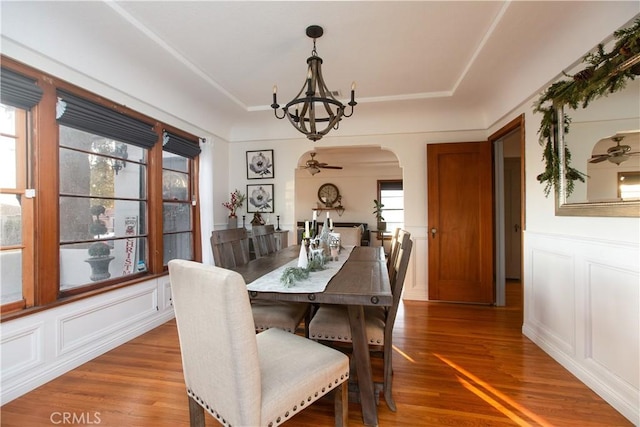 dining area with hardwood / wood-style flooring and ceiling fan with notable chandelier