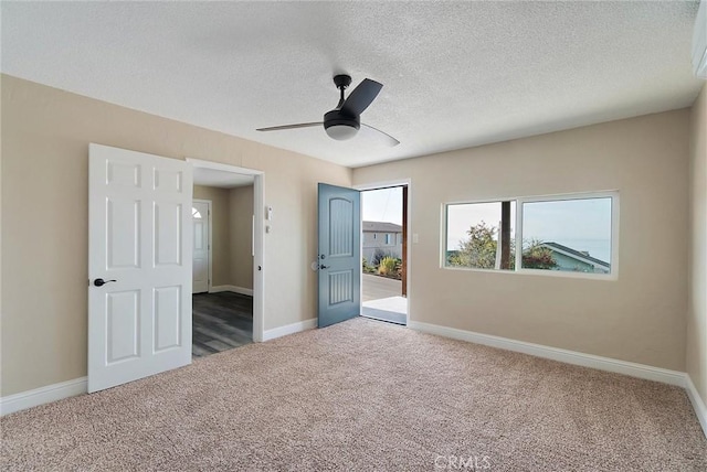 unfurnished bedroom with a textured ceiling, ceiling fan, and dark colored carpet