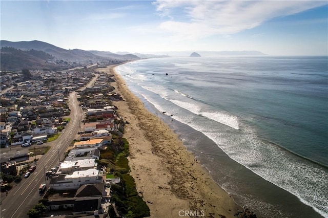 drone / aerial view with a water and mountain view and a view of the beach