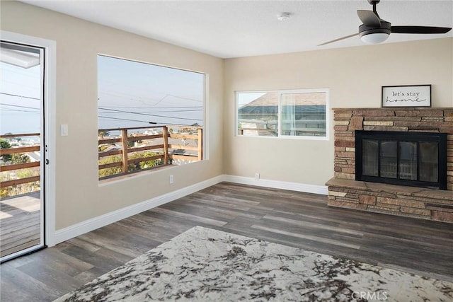 living room with a fireplace, ceiling fan, and dark wood-type flooring