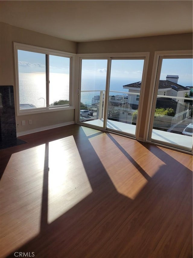 unfurnished living room featuring a water view and hardwood / wood-style floors