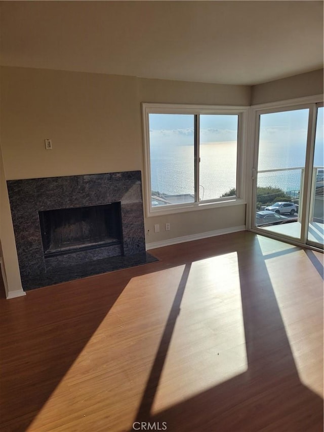 unfurnished living room with hardwood / wood-style flooring, a premium fireplace, and a water view