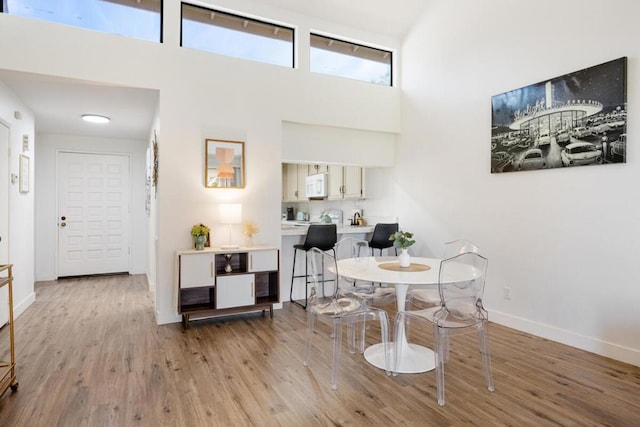 dining area with light hardwood / wood-style flooring and a towering ceiling