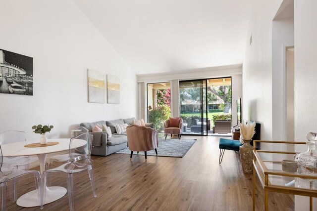 living room featuring high vaulted ceiling and wood-type flooring