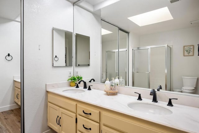 bathroom featuring vanity, a skylight, toilet, walk in shower, and wood-type flooring