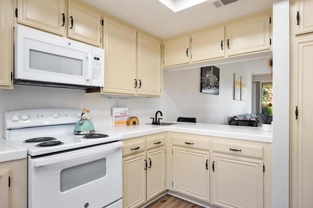 kitchen featuring white appliances, cream cabinets, sink, light hardwood / wood-style flooring, and tile counters